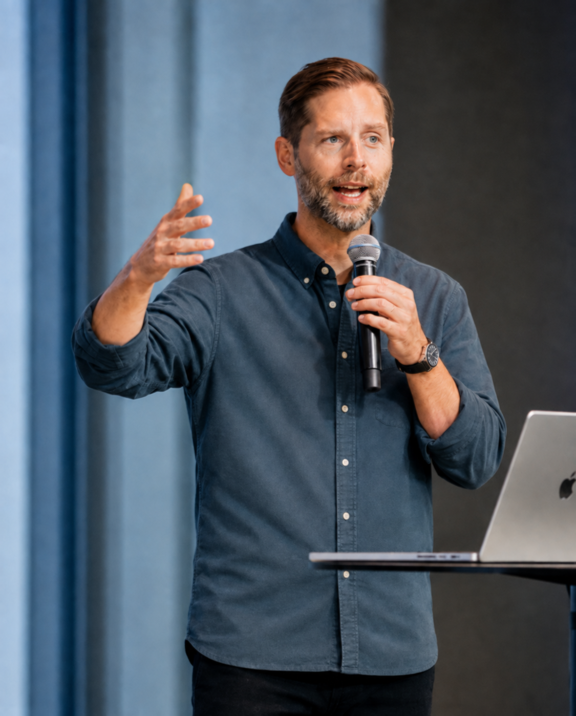 Adam Treister speaking on stage with a microphone